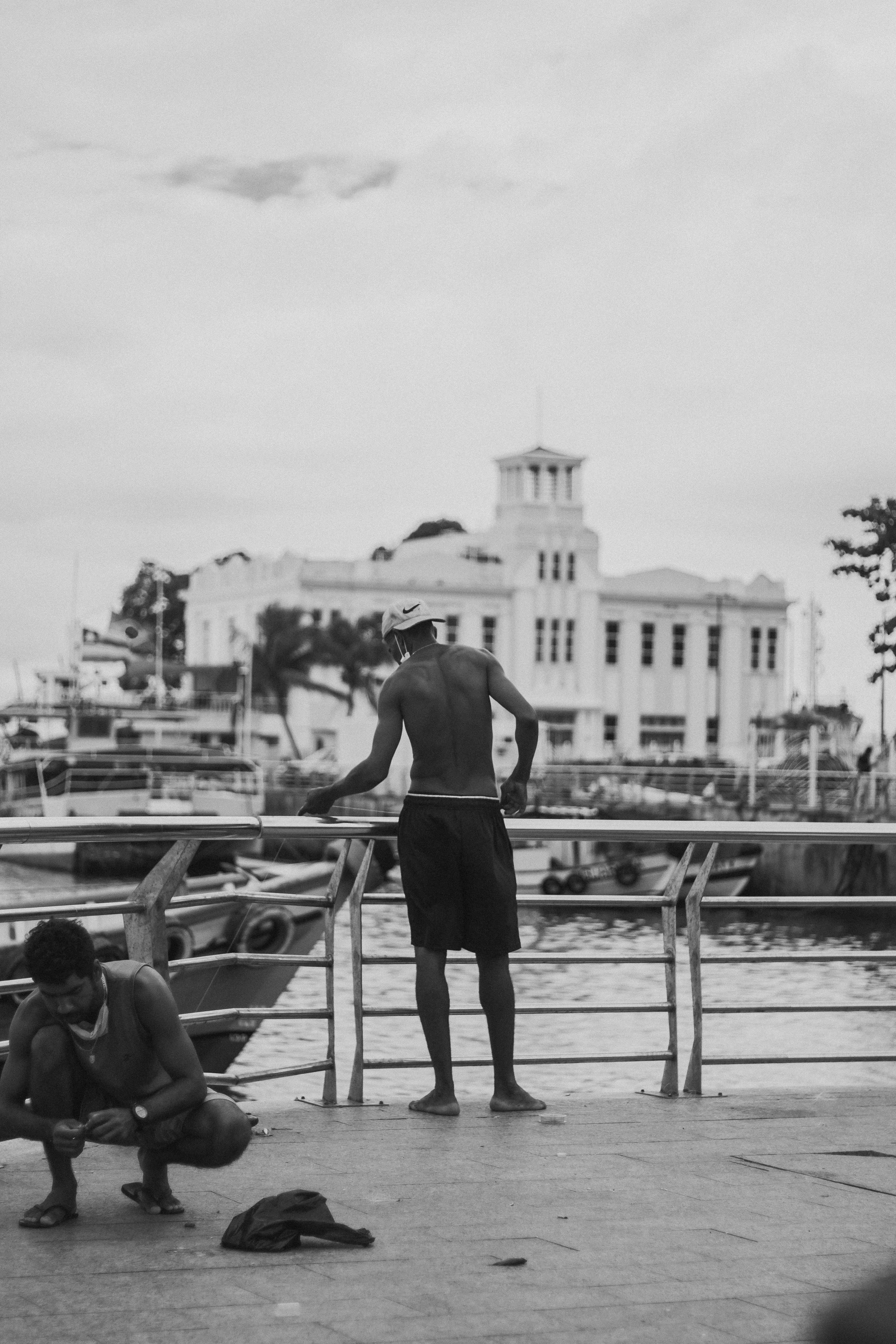 grayscale photo of man and woman walking on dock